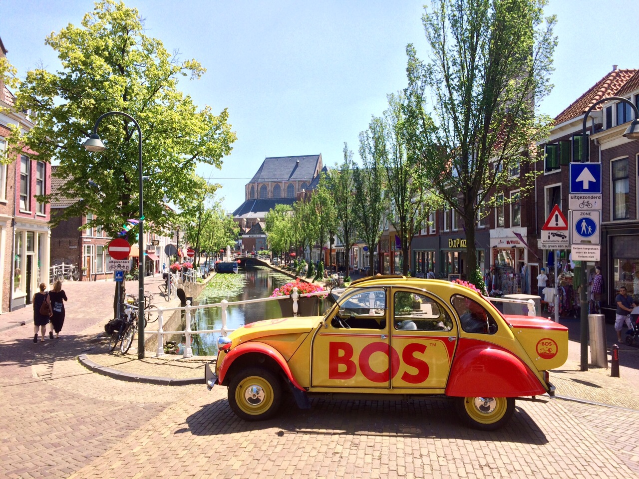 The BOS-branded yellow and red Citroën 2CV parked on a European canal street