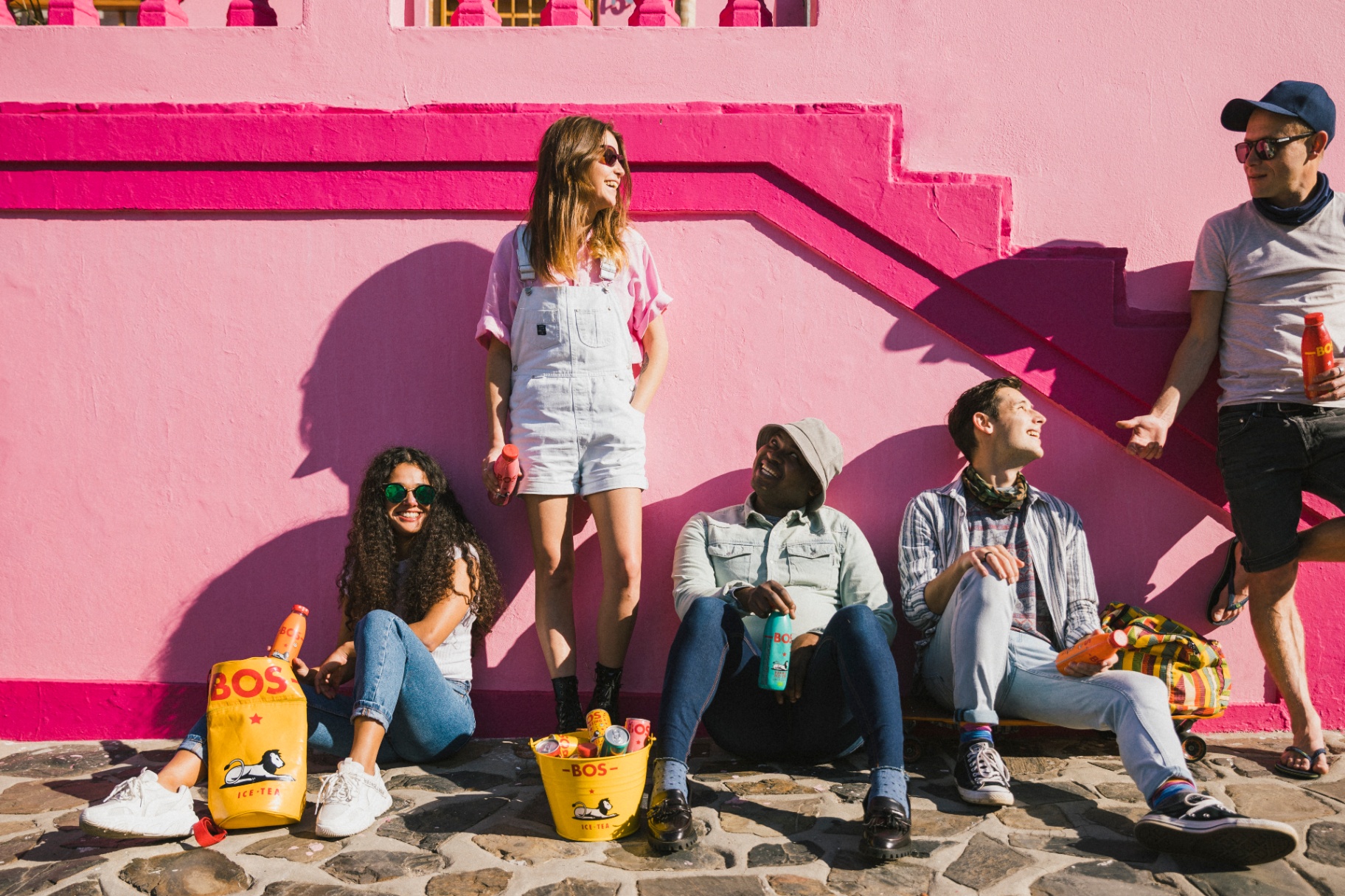 Friends gathered against the iconic pink Bo-Kaap wall in Cape Town with BOS rooibos ice tea