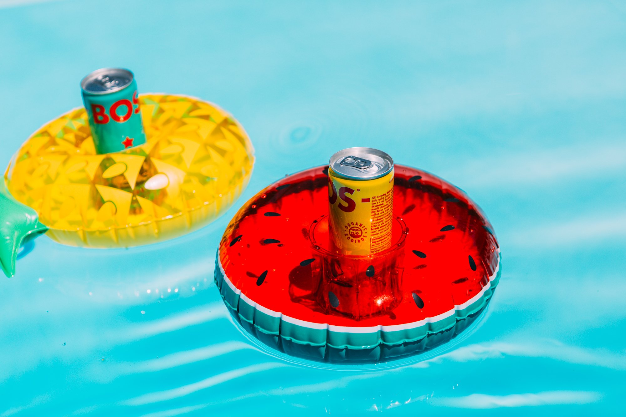 BOS rooibos cans floating on inflatable watermelon and pineapple pool floats